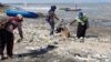 Para relawan memunguti sampah plastik yang banyak berserakan di pantai Kenjeran sisi timur Jembatan Suramadu (Foto: VOA/Petrus Riski)