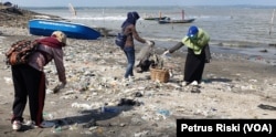 Para relawan memunguti sampah plastik yang banyak berserakan di pantai Kenjeran sisi timur Jembatan Suramadu (Petrus Riski/VOA)