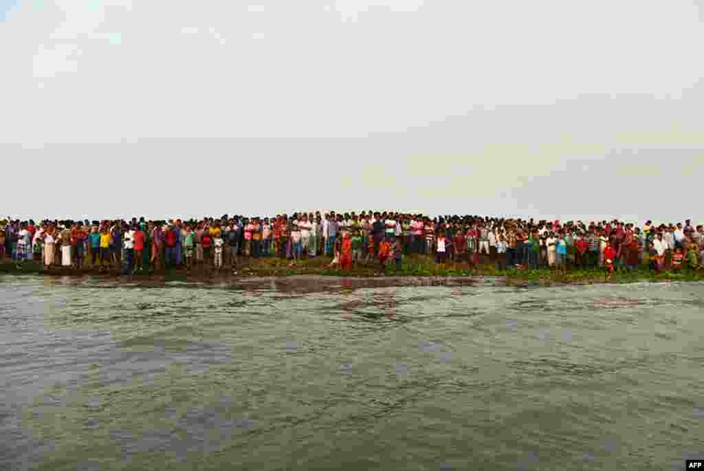 Bangladeshi residents gather near to the site where a ferry capsized and sank in bad weather on the river Meghna in Munshiganj district, some 50 kilometres (30 miles) south of the Bangladeshi capital Dhaka. At least ten people dead and hundreds more missing, police and officials said.