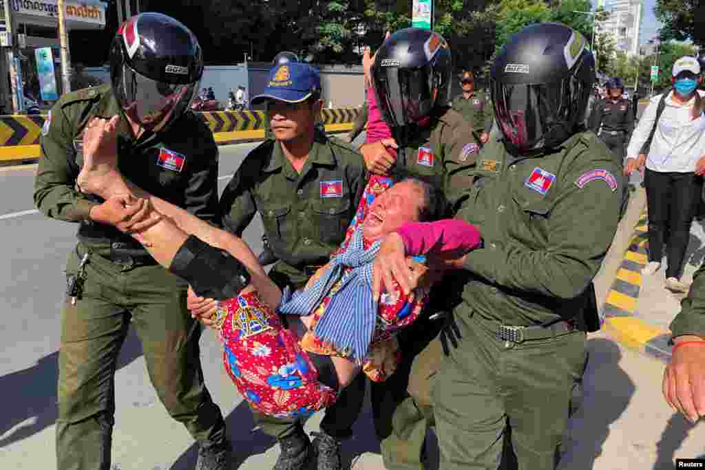 A woman is carried by police officers after security guards broke up a small protest near the Chinese embassy opposing alleged plans to boost Beijing&#39;s military presence in the country, in Phnom Penh, Cambodia. (Reuters)