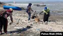 Para relawan memunguti sampah plastik yang banyak berserakan di pantai Kenjeran sisi timur Jembatan Suramadu (Foto: VOA/Petrus Riski)