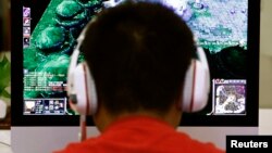 A man plays a computer game at an internet cafe in Beijing May 9, 2014. As growing numbers of young people in China immerse themselves in the cyber world, spending hours playing games online, worried parents are increasingly turning to boot camps to crush