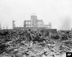 FILE - In this Sept. 8, 1945 file photo, an allied correspondent stands in the rubble in front of the shell of a building that once was a movie theater in Hiroshima, Japan, a month after the first atomic bomb ever used in warfare was dropped by the U.S., Aug. 6, 1945.