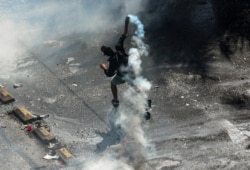 An anti-government demonstrator throws a tear gas canister back at the police during a protest in Santiago, Chile, Oct. 22, 2019.