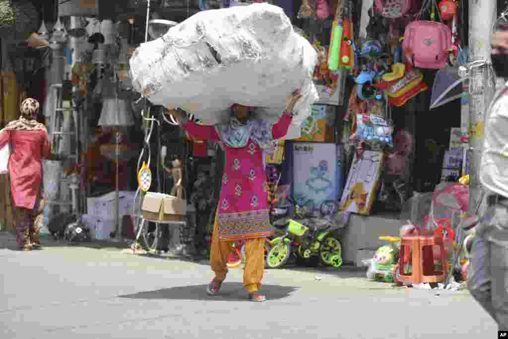 A laborer carries a load of plastic toys at a market in Jammu, India. 
