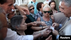 Pensioners are given priority tickets by a National Bank branch manager (R), as they wait to receive part of their pensions in Athens, Greece July 13, 2015. 