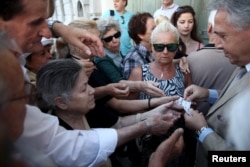 Pensioners are given priority tickets by a National Bank branch manager (R), as they wait to receive part of their pensions in Athens, Greece July 13, 2015.