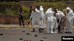 Forensic policemen inspect the site of a suicide bomb attack at a parade square in Sanaa, Yemen, May 21, 2012. 