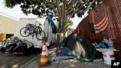 FILE - A RV vehicle is parked next to a tent on the streets in an industrial area of Los Angeles, Wednesday, July 31, 2019. (AP Photo/Damian Dovarganes)