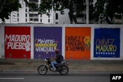 A motorcyclist rides past a campaign mural of Venezuelan President Nicolas Maduro in Caracas on July 3, 2024.