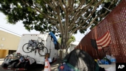 FILE - A RV vehicle is parked next to a tent on the streets in an industrial area of Los Angeles, Wednesday, July 31, 2019. (AP Photo/Damian Dovarganes)