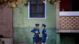 North Korean traffic police women chat next to a residential building while off duty in Pyongyang.
