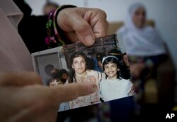 In this Aug. 8, 2018 photo, Fadwa Tlaib, an aunt of Rashida Tlaib points to a young Rashida Tliab in a 1987 picture with her mother Fatima and brother Nader, at the family house, in the West Bank village of Beit Our al-Foqa.