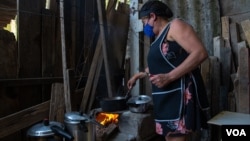 A woman cooks on a wood stove in the outskirts of São Paulo, Nov. 14, 2021. (Yan Boechat/VOA) 