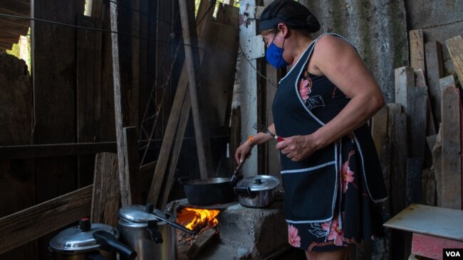 A woman cooks on a wood stove in the outskirts of São Paulo, Nov. 14, 2021. (Yan Boechat/VOA)
