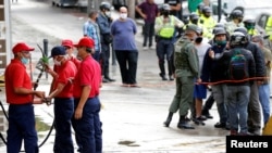 Un grupo de trabajadores de la estatal Pdvsa repara un dispensador de gasolina en Caracas, después de que el gobierno elevara el precio del combustible en enero de 2020.