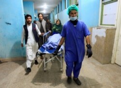 Afghan men transport the body of one of three female media workers who were shot and killed by an unknown gunmen, at a hospital in Jalalabad, Afghanistan, March 2, 2021.