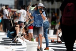 A volunteer uses a mask to cover his face while painting a 'Black Lives Matter' mural near the State Capitol on June 12, 2020, in Denver, Colorado