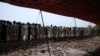 FILE - Men fleeing from the military offensive against Pakistani militants in North Waziristan queue to get relief handouts from a storage tent of the World Food Program at a distribution point for internally displaced persons in Bannu, located in Pakistan's Khyber-Pakhtunkhwa province, July 6, 2014.