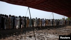 FILE - Men fleeing from the military offensive against Pakistani militants in North Waziristan queue to get relief handouts from a storage tent of the World Food Program at a distribution point for internally displaced persons in Bannu, located in Pakistan's Khyber-Pakhtunkhwa province, July 6, 2014.