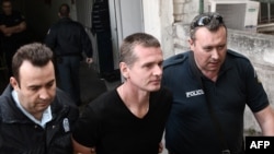 Warga negara Rusia Alexander Vinnik (tengah) digiring oleh anggota polisi saat tiba di gedung pengadilan di Thessaloniki, Yunani, pada 4 Oktober 2017. (Foto: AFP/Sakis Mitrolidis)