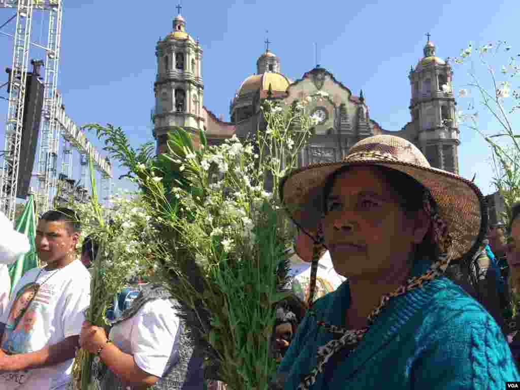 Mujer mexicana lleva flores para dejar en el altar de la Virgen de Guadalupe antes de la llegada del papa Francisco.
