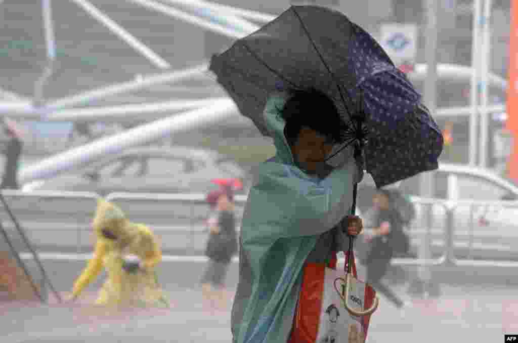 A woman uses an umbrella against strong wind and rain brought by typhoon Dujuan in the Tamshui district, New Taipei City. More than 7,000 people were evacuated in Taiwan as the &#39;super typhoon&#39; swirled towards the island, gathering strength as it bore down on the east coast.