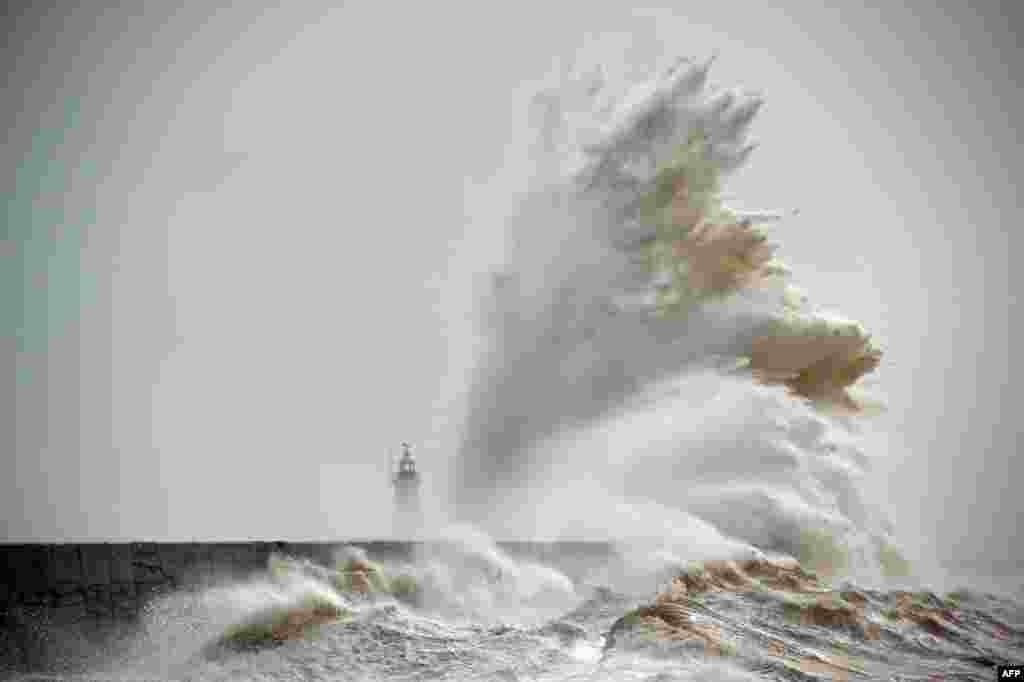Waves crash over the Newhaven Lighthouse on the south coast of England as the latest storm hits the country.