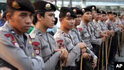 FILE - Indonesian police stand guard ahead of a planned protest at a major intersection in Jakarta, July 22, 2014. 