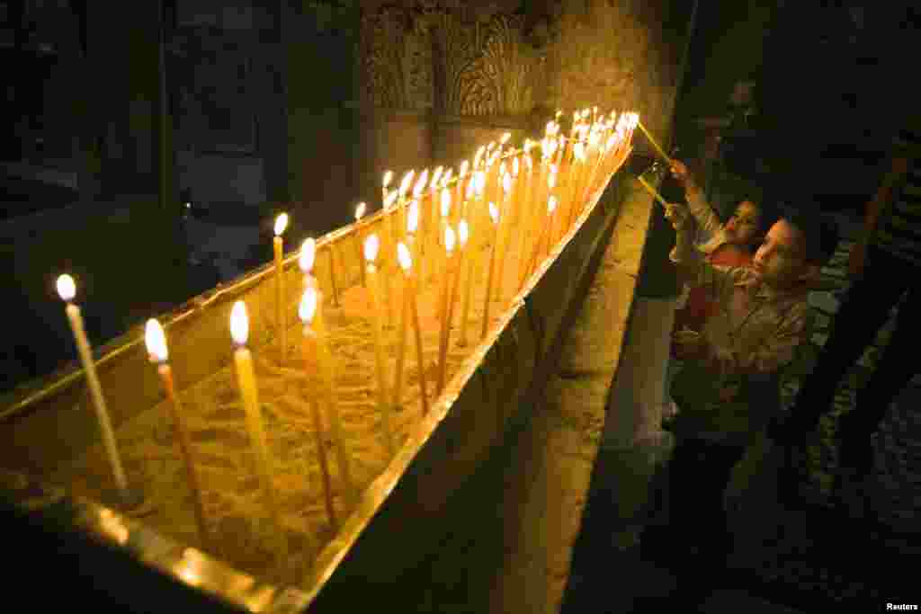 Dua orang anak menyalakan lilin pada misa Paskah di gereja Holy Sepulchre atau gereja Makam Kudus di kota tua Yerusalem.