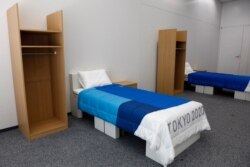 FILE - Two sets of bedroom furniture, including cardboard beds, are shown in an Athletes Village display room in Tokyo, Jan. 9, 2020.