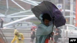 一名妇女用雨伞来遮挡強風和暴雨（2015年，9月28日）