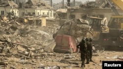 Members of security forces stand near damaged buildings and vehicles after a blast in Ibadan, Nigeria, January 17, 2024. 