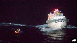 In this photo released by the 10th Regional Japan Coast Guard Headquarters, a Filipino crewmember of a Panamanian cargo ship is rescued by Japanese Coast Guard members in the waters off the Amami Oshima, Japan, Sept. 2, 2020.
