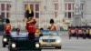 Thailand's King Maha Vajiralongkorn, standing in a car right, and Queen Suthida, standing in a car left, review the honor guard in Bangkok, Thailand, Dec. 3, 2024.