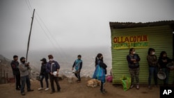 Residents wait in line at a "community pot" in the Nueva Esperanza neighborhood of Lima, Peru, June 17, 2020. For many residents the "community pot" is their only defense against a hunger that's become a constant amid the COVID-19 pandemic.