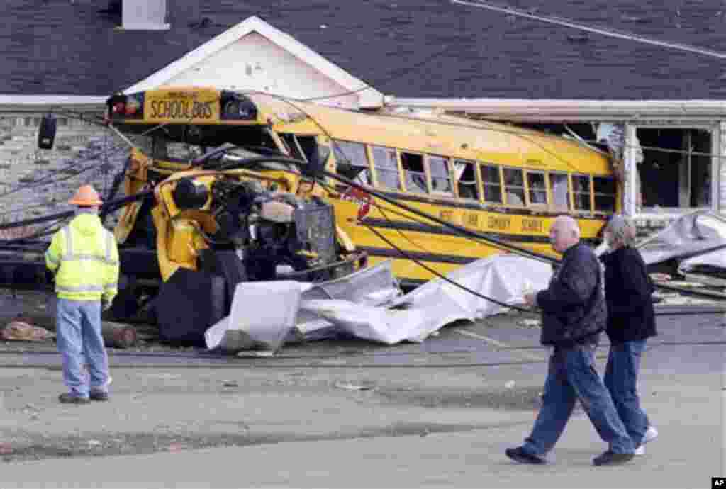 Residents walk past a school bus destroyed by tornado in Henryville, Ind., Sunday, March 4, 2012.