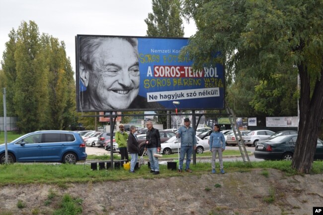 FILE - Activists from the Egyutt (Together) opposition party stand in front of billboards of the government's campaign against George Soros and his support for migration in Budapest, Oct. 5, 2017.