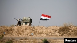 A military vehicle of the Iraqi security forces is seen next to an Iraqi flag in Falluja, Iraq, June 13, 2016. An operation to liberate the city from Islamic State militants is now in its thrid week.