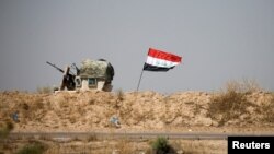 A military vehicle of the Iraqi security forces is seen next to an Iraqi flag in Fallujah, Iraq, June 13, 2016. An operation to liberate the city from Islamic State militants is now in its third week.