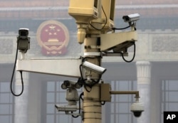 A pole attached with security cameras to monitor Tiananmen Square stands against a backdrop of the Chinese Communist Party emblem on the Great Hall of the People in Beijing, Oct. 20, 2014.