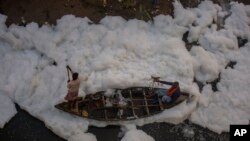 A man rows a boat in the Yamuna River, which is covered with a chemical foam caused by industrial and domestic pollution, during the Chhath Puja festival in New Delhi, India.