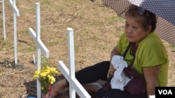 A woman remembers her loved one at the mass-burial site marked with 3,000 crosses for the people who perished when super typhoon Haiyan smashed through Tacloban City and the central Philippines. Holy Cross Memorial Park, Tacloban. Nov. 8, 2014. (Simone Orenain/VOA)