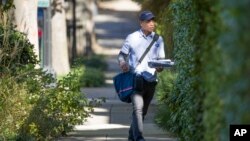 FILE - A letter carrier with the U.S. Postal Service makes his rounds near the home of former president Barack Obama, Oct. 24, 2018, in Washington. 