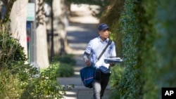 Description: FILE - A letter carrier with the U.S. Postal Service makes his rounds near the home of former president Barack Obama, Oct. 24, 2018, in Washington. The U.S. Secret Service says agents have intercepted packages containing "possible explosive devices"