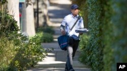 FILE - A letter carrier with the U.S. Postal Service makes his rounds near the home of former president Barack Obama, Oct. 24, 2018, in Washington. 