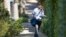 FILE - A letter carrier with the U.S. Postal Service makes his rounds near the home of former president Barack Obama, Oct. 24, 2018, in Washington. 