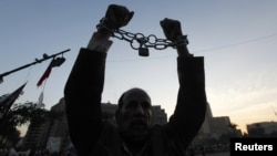 A man holds up his chained hands as he protests against Egypt's President Mohamed Morsi at Tahrir Square in Cairo, Egypt, December 18, 2012.