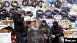 Pro-European protesters warm themselves at a fire in front of barricade in central Kyiv, Dec. 16, 2013.