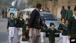 Yon polisye an inifòm ap akonpaye yon gwoup elèv ki sòti nan lekòl Taliban yo atake nan vil Peshawar, nan Pakistan. (Foto: Madi 16 desanm 2014). 